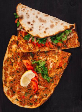 Kıyılmış et, domates, maydanoz ve koyu ahşap masada limonla servis edilen baharatlı Türk lahana ezmesi.