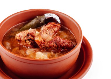 Et ve patatesli Aromatik çorba kil bir kasede servis edilir, kırsal ve lezzetli bir yemek deneyimi sunar.