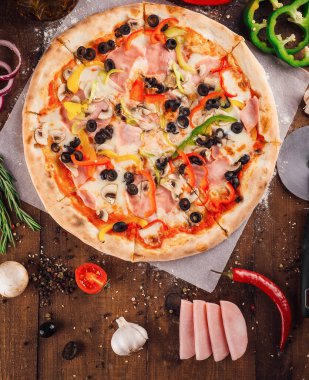 Taze malzemelerle çevrili ahşap bir masada duran jambonlu ve mantarlı lezzetli pizza.