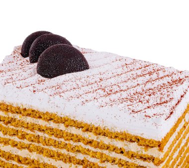 Ağız sulandıran ballı kek, beyaz arka planda izole edilmiş çikolata ve kakao tozuyla süslenir.