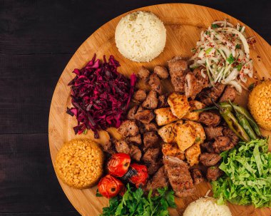Tahta tabakta pirinç ve sebzelerle servis edilen Türk kebabı.