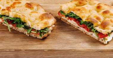 Kesme tahtasının üzerinde sebzeli ve peynirli İtalyan panini.