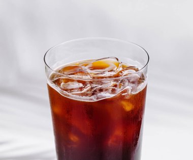 Tropikal bitki gölgesiyle beyaz küpün üzerinde duran soğuk kahve bardağını tazeleyeceğim.