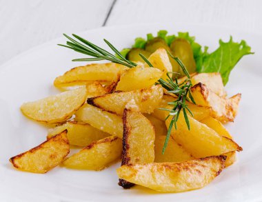 Tahta masada beyaz tabakta duran biberiyeli leziz kızarmış patatesler.