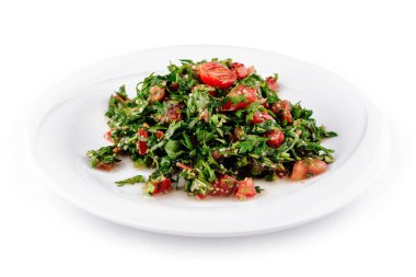 Maydanoz, domates ve diğer taze malzemelerden oluşan, beyaz bir tabakta taze yapılmış tabbouleh salatası.