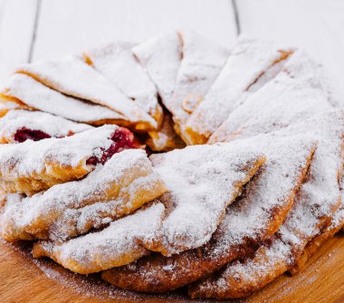 Beyaz köy masasında ahşap kesme tahtasının üzerinde şeker tozlu nefis ev yapımı vişneli turta.