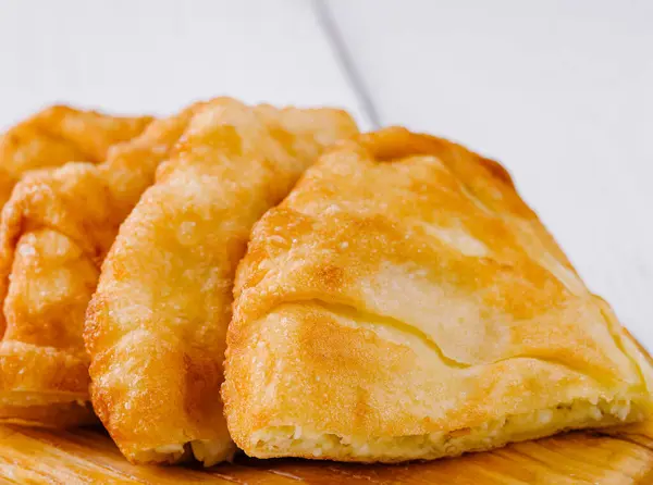 stock image Delicious langos, a deep-fried dough, served on a wooden plate, a popular street food in hungary