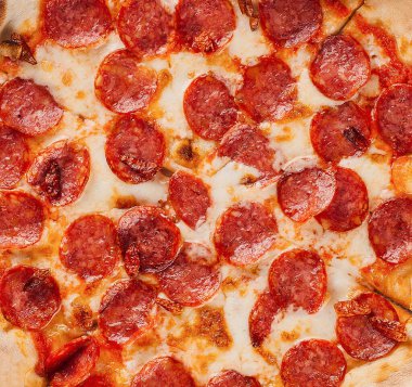 Lezzetli taze fırınlanmış pepperoni pizza ve erimiş mozzarella peyniri pizza dilimleri ile dilimleniyor.