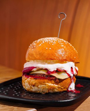 Siyah tabakta malzemelerle sulu bir gurme hamburgerin yakın çekimi.