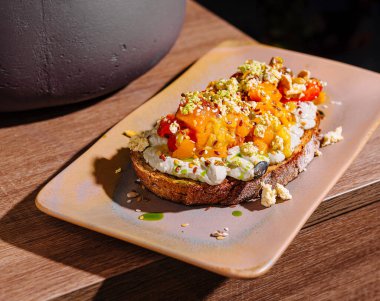 Lezzetli bruschetta, sarı domates ezmesi, bitkiler ve baharatlar bir tabakta duruyor.