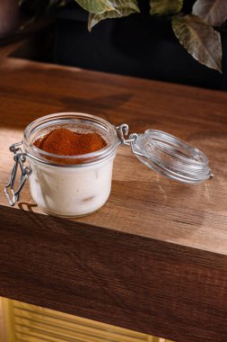 Klasik İtalyan tiramisu tatlısı cam kavanozda ve tahta masa yüzeyinde açık kapağı var.