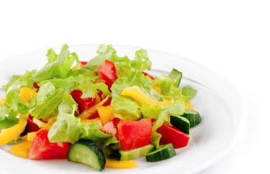 Beyaz tabakta marul, domates, salatalık ve biberden yapılmış taze salata servis edilir.