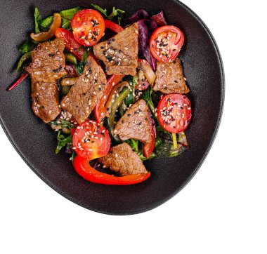 Susam tohumlu biftek ve sebzeli sıcak salata, siyah tabakta servis edilir, beyaz arka planda çekilir.