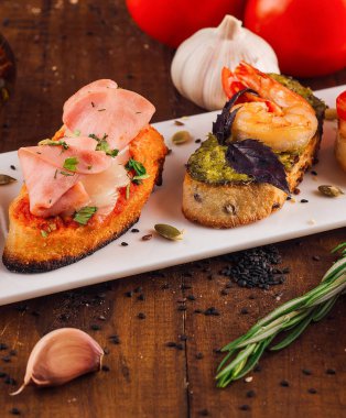 Tabak çeşitli lezzetli İtalyan aperatifleri sunuyor kızarmış baget dilimleri üzerinde bruschetta.