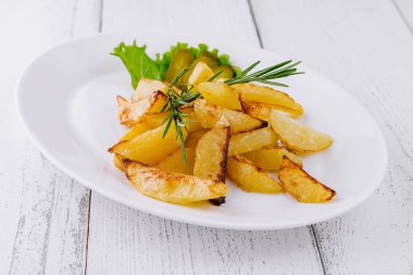 Tahta masada beyaz tabakta duran biberiyeli leziz kızarmış patatesler.