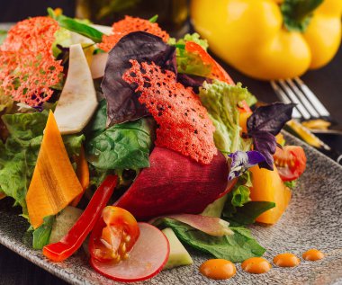 Restoran masasında pancar cipsi ve yenilebilir çiçekli renkli vejetaryen salatası servis edilir.