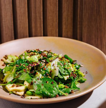 Tahta arka planda kinoa ve avokado ile taze vejetaryen yemek kasesi.