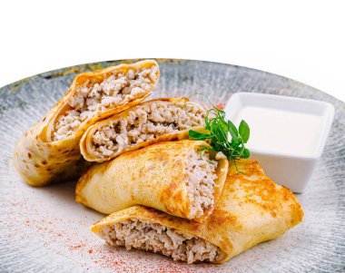 Gri bir tabağa ekşi kremayla doldurulmuş ve yeşilliklerle süslenmiş gözlemeler.