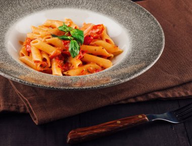 Lezzetli makarna tabağı domates sosu ve fesleğen garnitürle sunulur.