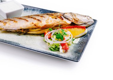 Izgara levrek taze salata, limon, şifalı otlar ve beyaz sosla servis edilir.