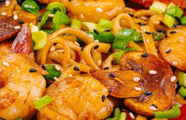 Kızarmış erişte, karides, sebze ve susam tohumları.