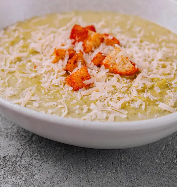 stock image Broccoli cream soup served in a white bowl on a gray background, perfect for a food blog or menu