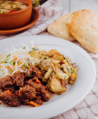 Kızarmış patates ve lahana salatasıyla servis edilen leziz sığır eti güveci.