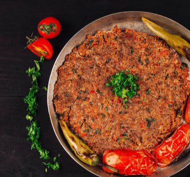 Türk mutfağı kıymalı kofte baharatlı köfteli domates ve biberli sade ahşap masada servis ediliyor.