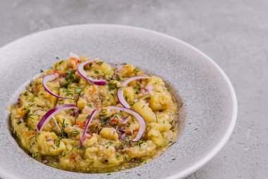 Baba Ghanoush kırmızı soğan ve otlarla süslenmiş, modern bir restoranda servis ediliyor.