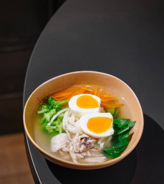 Modern bir restoranda servis edilen sebzeli ve yumurtalı baharatlı tavuk çorbası.