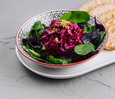 Cevizli pancar salatası ve roka kızarmış ekmekle birlikte beyaz bir tabakta servis edilir.