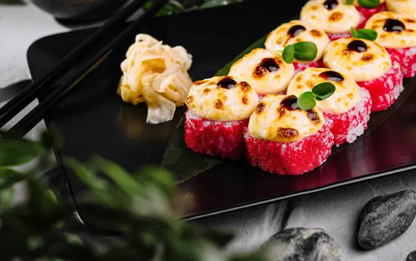 stock image Elegant setup of torched sushi with vibrant garnishes and soy sauce on a stylish black slate