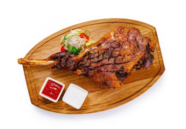 Ahşap tahtada servis edilen ızgara kuzu şişi, domates, marul salatası ve sos.