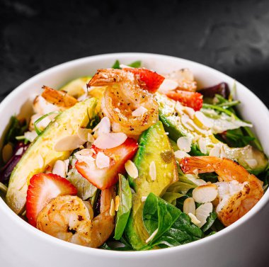 Çilekli lezzetli karides salatası, avokado ve beyaz kasede yeşiller.