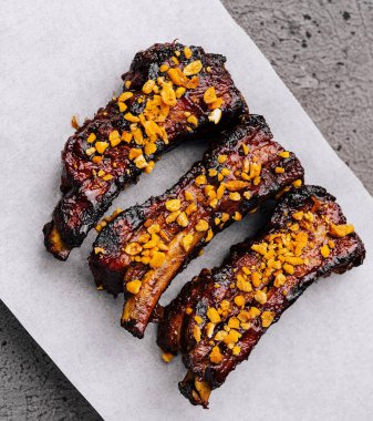 Delicious sticky pork ribs garnished with nuts on rustic paper, ready to serve