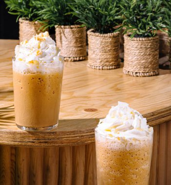 İki ferahlatıcı buzlu kahve frappuccino içeceği üstüne krema ve karamel serpiştirilmiş.