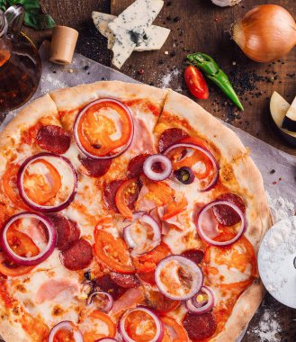 Eritilmiş mozarella peynirli, domates dilimli, jambonlu ve kırmızı soğanlı taze pişmiş pizza.