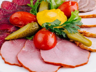 Dilimlenmiş et ve sebze tabağında servis edilir.