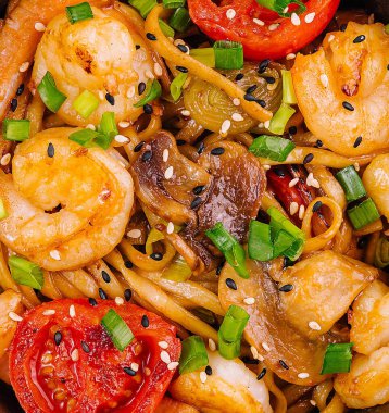 Siyah ve beyaz susam tohumlarıyla süslenmiş karides ve mantarlı Udon eriştesi harika bir öğle yemeği olur.