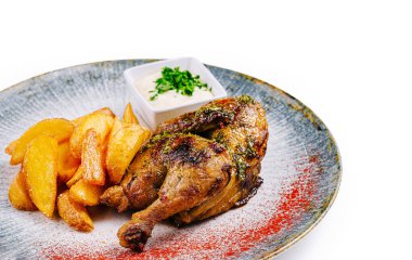 Kızarmış tavuk, yanında altın patatesle servis edilir ve bir tabak beyaz sos, baharat ve otlarla tatlandırılır.