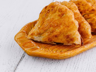 Birkaç altın-kahverengi chebureki hamur işi ahşap bir tabağa konur. Lezzetli tatlardan bahseden baştan çıkarıcı bir aroma yayar.