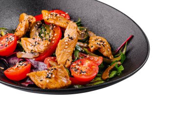 Izgara tavuklu taze salata, kiraz domatesleri, roka ve ıspanak, susam tohumuyla tatlandırılmış, siyah tabakta servis ediliyor.