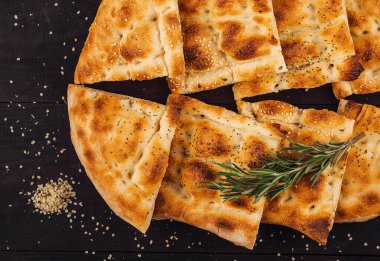 Türk ramazan pide ekmeği, susamlı ve biberiyeli koyu ahşap bir masada servis ediliyor