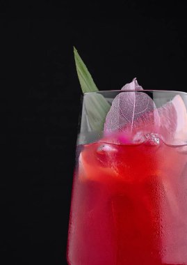 Buzlu, greyfurtlu ve yapraklı bir bardakta taze kırmızı kokteyl servis edilir.