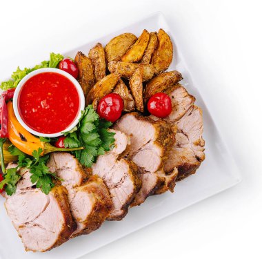 Patates, turşu ve keskin sosla servis edilen leziz kızarmış domuz eti.