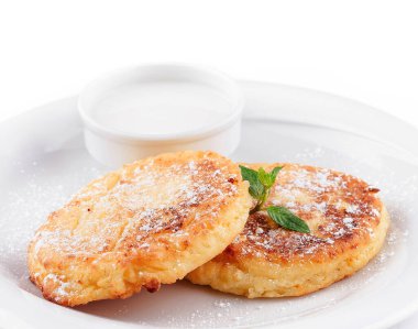 İki lezzetli süzme peynir pudra şekeri, ekşi krema ve beyaz tabakta naneli krep.