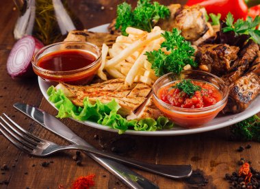 Kızarmış tavuk göğsü, patates kızartması ve sosla servis edilir.