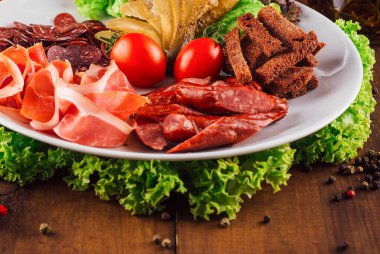 Ahşap bir masada çeşitli füme etler, turşular ve çavdar ekmeği ile lezzetli et tabağı servis edilir.