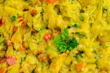 Taze guacamole olgun avokadolar, doğranmış domatesler ve kişniş ile hazırlanıyor. Canlı bir açık hava buluşmasında canlı renkler ve tatlar vurgulanıyor..