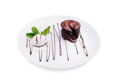 Zengin bir çikolatalı tatlı bir kepçe dondurma ve bir tutam nane ile kaplanır. Koyu çikolata sosu serpintileri sanatsal bir dokunuş ekler ve görsel olarak çekici kılar..